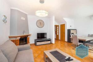 a living room with a couch and a clock on the wall at Vila Sul Dream Lodging in Albufeira