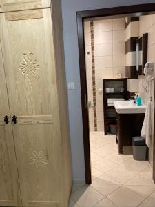 a bathroom with a door leading to a sink at Apartament Aleksander in Zakopane