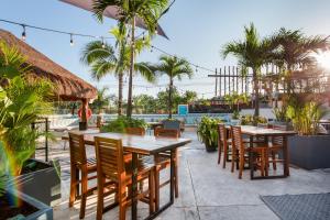 a patio with tables and chairs and palm trees at Mayan Monkey Tulum in Tulum