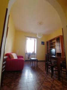 a living room with a red couch and a table at Due finestre sul cortile in Novi Ligure