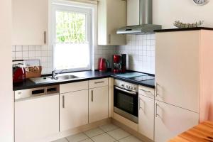 cocina con armarios blancos, fregadero y ventana en Semi-detached house, Lubmin en Lubmin