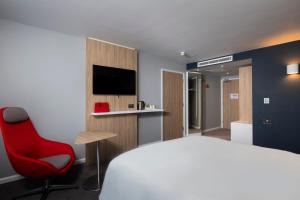 a hotel room with a bed and a red chair at Holiday Inn Express Edinburgh City West by IHG in Edinburgh