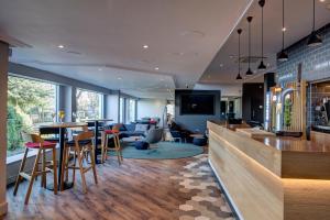 a restaurant with a bar with tables and chairs at Holiday Inn Express Edinburgh City West, an IHG Hotel in Edinburgh
