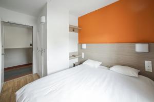 プレジールにあるPremière Classe Plaisir Gatinesのベッドルーム(オレンジ色のヘッドボード付きの大きな白いベッド付)