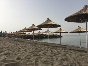 a group of straw umbrellas on a beach at Benjy’s Villa(B&B) in Shëngjin