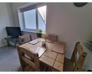 uma mesa de madeira e cadeiras num quarto com uma janela em Canal Side Retreat - 2 Bedroom Apartment em Heybridge