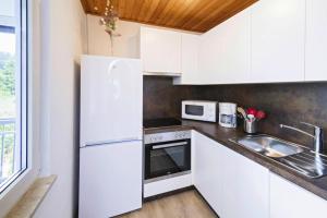 a white kitchen with a sink and a refrigerator at Apartment in St Kanzian am Klopeinersee with garden in Wasserhofen