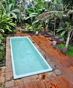 una piscina con sillas en una terraza de madera en Jataí Guest House en Ubatuba