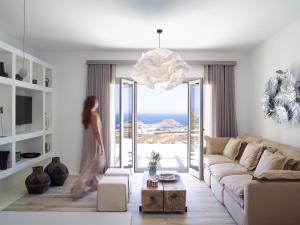 a woman walking through a living room with a couch at Soleila Mykonos Villa in Kalafatis