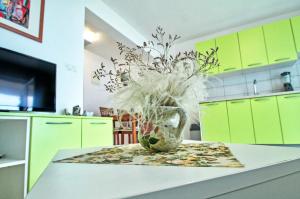 una cocina con armarios verdes y un jarrón con flores en Seashell Vinjerac, en Vinjerac