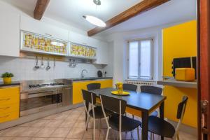 une cuisine avec des armoires jaunes, une table et des chaises dans l'établissement Central Ferrara Apartment, à Ferrare