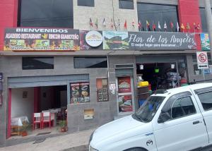une voiture blanche garée devant un restaurant dans l'établissement Hostal Flor de los Ángeles, à Guamote