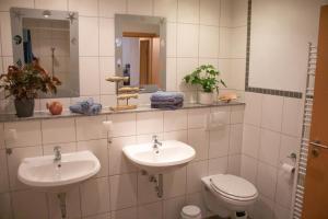 a bathroom with two sinks and a toilet at Ferienanlage Inselzauber in Gustow +25 photos