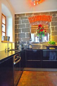 a kitchen with a stone wall and black cabinets at Landhaus Austria, Fehring in Fehring