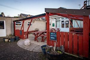 un edificio rosso con tavolo da picnic e cartello di The Ben Mhor Hotel, Bar & Restaurant a Grantown on Spey