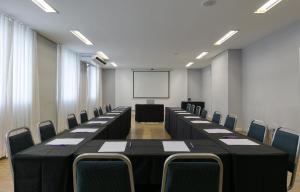 uma sala de conferências com mesas e cadeiras e um quadro branco em Mercure Belo Horizonte Savassi em Belo Horizonte