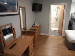 1 dormitorio con tocador, espejo y cama en Standing Stones Lodge, en Belfast