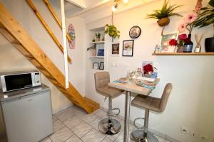 a kitchen with a table with chairs and a microwave at Duplex climatisé, balcon, check-in autonome in Renage