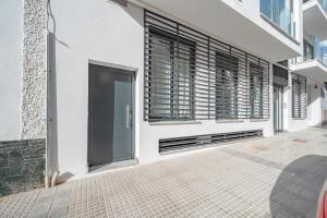 Un edificio blanco con ventanas con contraventanas negras y una acera. en Doña Elvira Malasaña, en Málaga