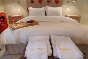 ein weißes Bett mit zwei weißen Handtüchern darauf in der Unterkunft Black Diamond Luxury Beachfront Villa Melina in Kalívia Thorikoú
