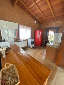uma cozinha com uma mesa de madeira e um frigorífico vermelho em Casa Tapera Nova em Conceição do Ibitipoca