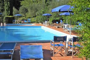 una piscina con sillas y sombrillas azules en Agriturismo La Scopa Montaione, en Montaione