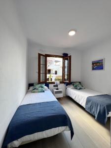 a bedroom with two beds and a window at Apartamentos El Bergantin Menorca Club in Fornells +37 photos