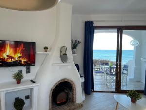 a living room with a fireplace with a view of the ocean at Apartamentos El Bergantin Menorca Club in Fornells