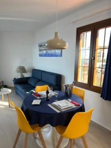 a living room with a table and yellow chairs at Apartamentos El Bergantin Menorca Club in Fornells