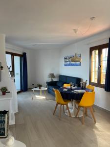 a living room with a blue couch and yellow chairs at Apartamentos El Bergantin Menorca Club in Fornells