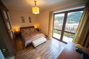 a bedroom with a bed and a large window at Apartamenty Nad Dunajcem in Szczawnica