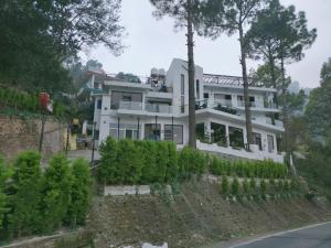 a white house on the side of a hill at The Golden Sunrise Hotel in Nainital
