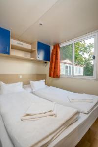 2 camas en una habitación con ventana en Lipicai Apartmanházak, en Szilvásvárad