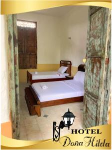 two twin beds in a room with a window at Hotel Doña Hilda in San Martín