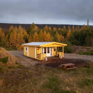 una casita amarilla en medio de un campo en Kaldá Lyngholt Holiday Homes en Egilsstadir