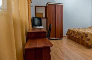 アドレルにあるMini Hotel Morskaya Skazkaのベッド、デスク、テレビが備わる客室です。