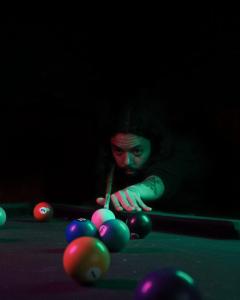a man playing billiard with a cue on a pool table at Quintal Hostel & Bar in Sao Paulo