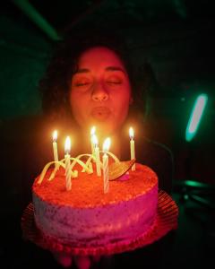 een vrouw houdt een verjaardagstaart vast met kaarsen bij Quintal Hostel & Bar in Sao Paulo