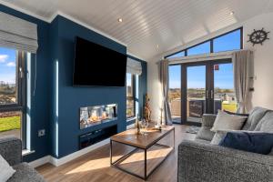 a living room with a blue wall with a fireplace at Hiraeth - Luxury Lodge with Hot Tub, Close to Beach in Penally