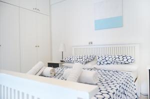 a white bedroom with two beds with blue and white pillows at Mia's Cove in Paphos +34 photos
