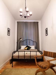 a bedroom with a bed with a chandelier and a chair at Centrum Apartament Stylowy in Świdnica