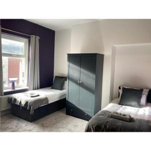 a bedroom with two beds and a cabinet and a window at Alexandra House in Goole