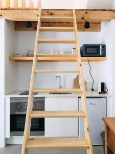 a ladder leading up to a kitchen with a bunk bed at Estudio do Loureiro in Vidigueira