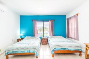 two beds in a room with a blue wall at Malecon Beach House in Progreso 1 block from beach in Progreso