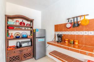 a kitchen with a refrigerator and a shelf with utensils at Malecon Beach House in Progreso 1 block from beach in Progreso +37 photos