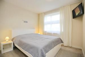 ein weißes Schlafzimmer mit einem Bett und einem Fenster in der Unterkunft Haffblick Wohnung 43 in Boltenhagen