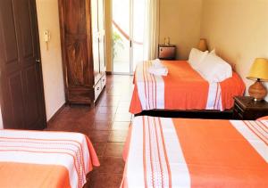 a hotel room with two beds with orange and white sheets at La Vivienda Villa in Santa Cruz Huatulco
