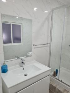 a white bathroom with a sink and a shower at Casa do Mestre in Setúbal