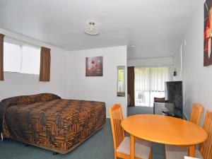 a room with a bed and a table and a bed at Celtic Motel in Foxton