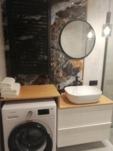 a bathroom with a washing machine and a mirror at Apartament River House in Szczecin